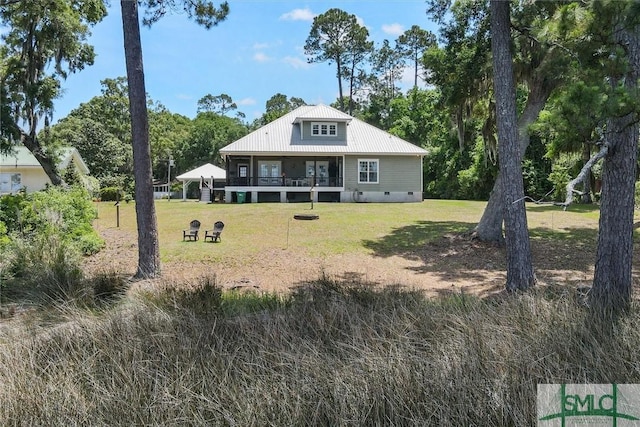 rear view of property with a yard, crawl space, and metal roof