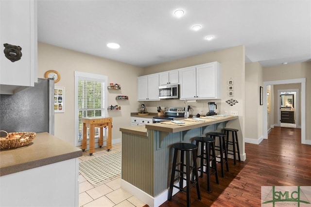 kitchen with white cabinets, stainless steel appliances, baseboards, and a breakfast bar