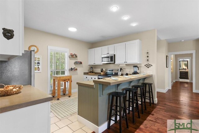1261 Otter Slide Loop NE, Townsend, GA 31331 - kitchen with stainless steel appliances, a kitchen bar, white cabinetry, baseboards, and recessed lighting