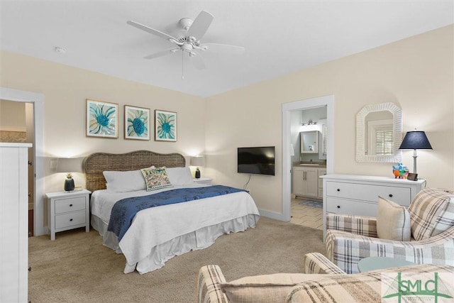 bedroom with baseboards, ensuite bathroom, light carpet, and ceiling fan