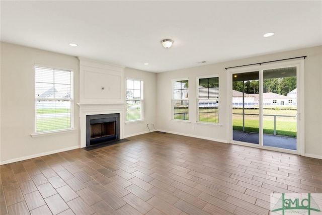 unfurnished living room with recessed lighting, baseboards, dark wood-style floors, and a fireplace