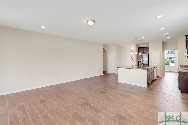 kitchen featuring stainless steel refrigerator with ice dispenser, open floor plan, recessed lighting, and light wood-type flooring