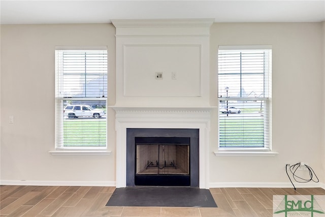 details featuring a fireplace with flush hearth, wood tiled floor, and baseboards