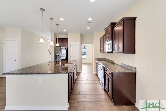 kitchen with a sink, an island with sink, stainless steel appliances, and dark brown cabinets
