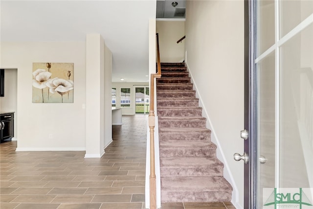 staircase featuring baseboards, wood finished floors, and visible vents