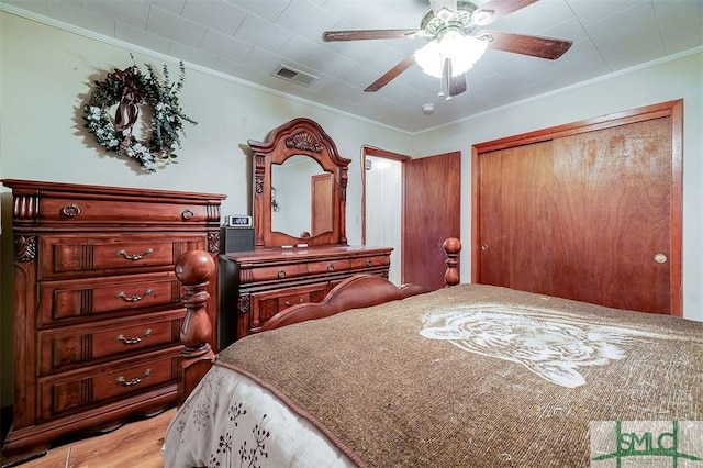 bedroom featuring a closet, ornamental molding, a ceiling fan, and visible vents