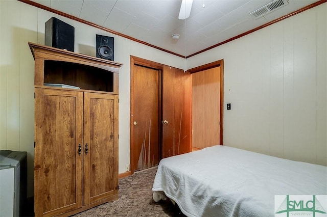 carpeted bedroom featuring visible vents, ornamental molding, ceiling fan, and a closet