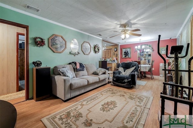 living area with crown molding, ceiling fan with notable chandelier, light wood-type flooring, and visible vents