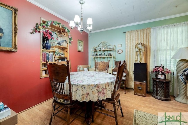 dining space with an inviting chandelier, ornamental molding, and light wood finished floors