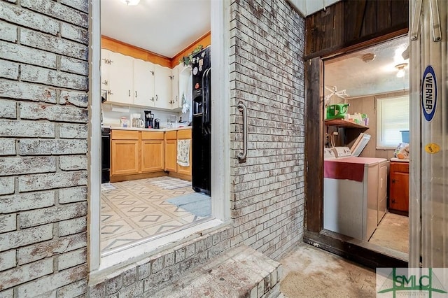 interior space with light countertops, separate washer and dryer, brick wall, and concrete floors