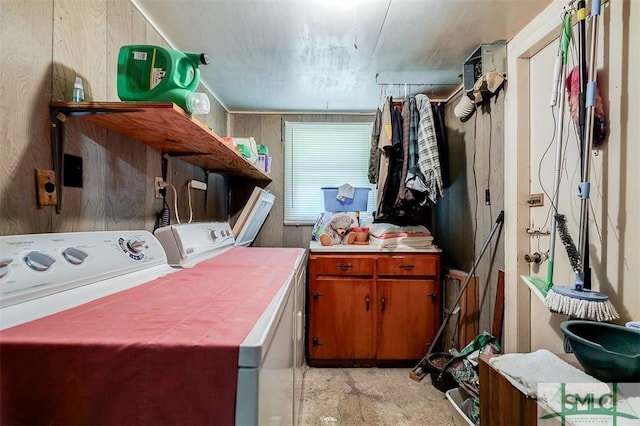 washroom featuring wooden walls, separate washer and dryer, and cabinet space