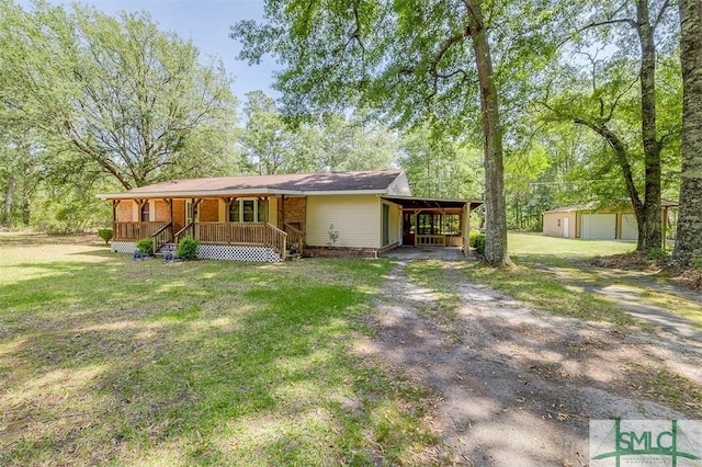 view of front of home with a front lawn, a porch, an outbuilding, a carport, and driveway