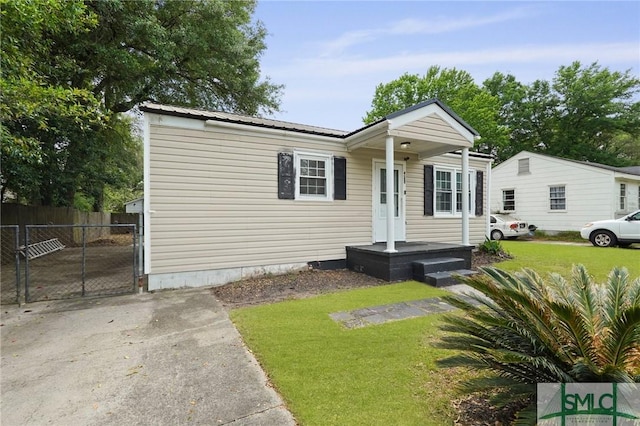 manufactured / mobile home with a gate, fence, a front yard, and metal roof