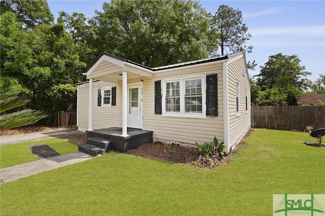 view of front facade featuring fence, metal roof, and a front lawn