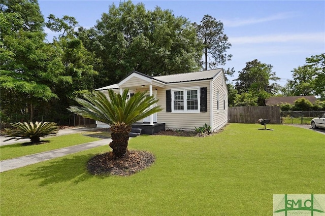 view of front of house featuring fence, a front yard, and metal roof