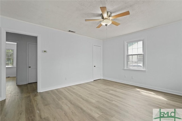 empty room featuring a healthy amount of sunlight, crown molding, ceiling fan, and wood finished floors