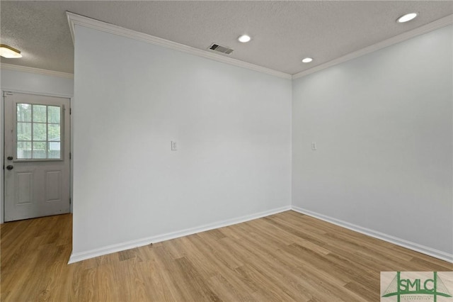 unfurnished room with visible vents, ornamental molding, light wood-style flooring, and baseboards