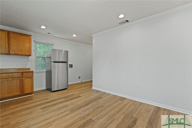 interior space with freestanding refrigerator, crown molding, visible vents, and light wood finished floors