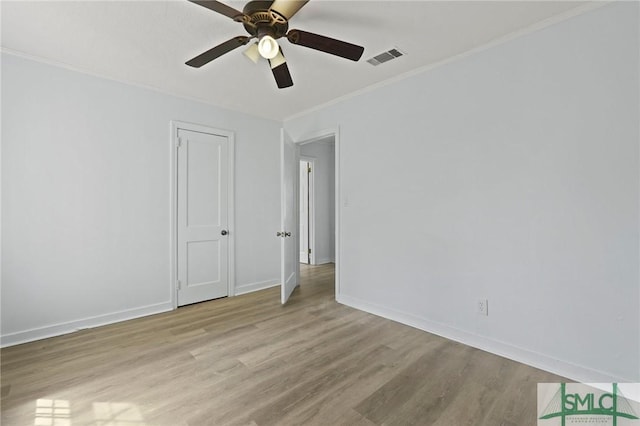 empty room featuring baseboards, a ceiling fan, light wood-style flooring, and crown molding