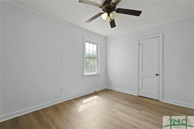 spare room with crown molding, ceiling fan, baseboards, and wood finished floors