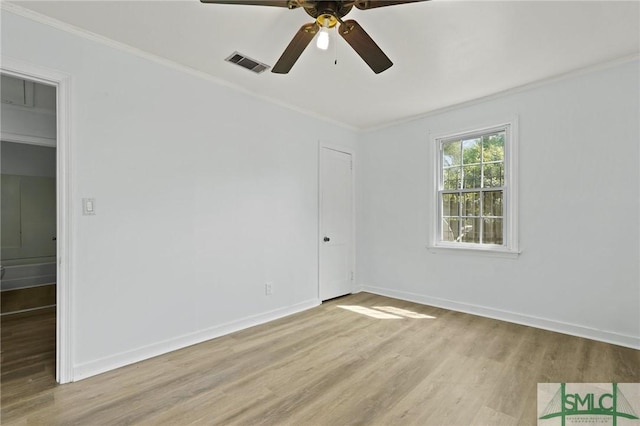 spare room featuring visible vents, ornamental molding, and light wood finished floors