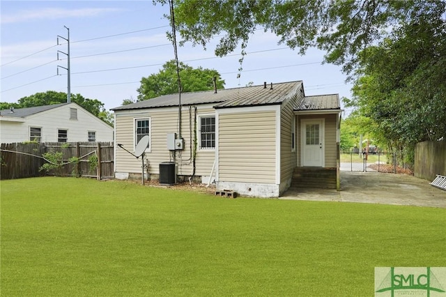 back of property featuring a lawn, fence, and metal roof