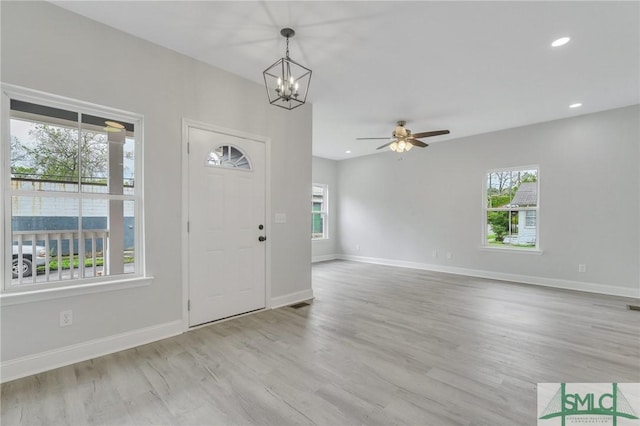 entryway with baseboards, ceiling fan with notable chandelier, wood finished floors, and a healthy amount of sunlight