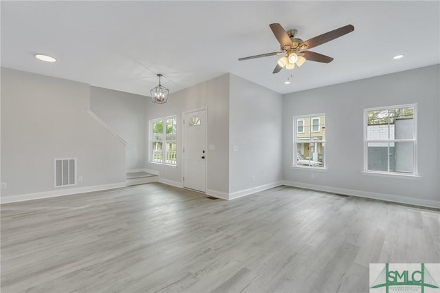 unfurnished living room with visible vents, baseboards, ceiling fan with notable chandelier, light wood finished floors, and recessed lighting