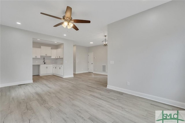 unfurnished living room featuring ceiling fan, baseboards, and light wood finished floors