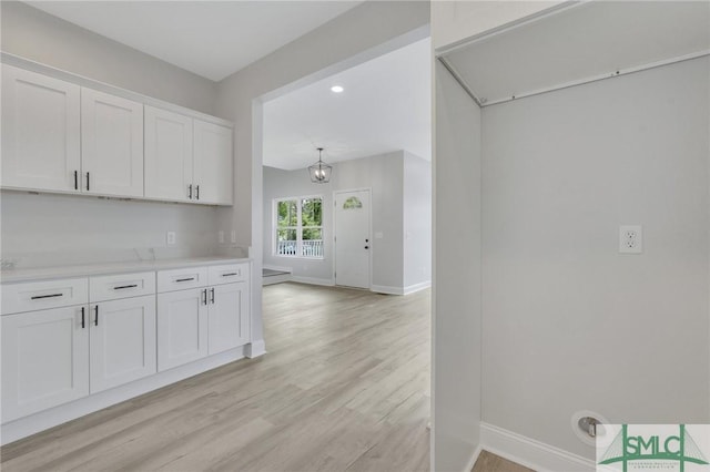 kitchen with light wood finished floors, light countertops, white cabinetry, baseboards, and recessed lighting