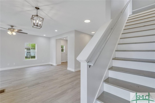 staircase with ceiling fan with notable chandelier, recessed lighting, baseboards, wood finished floors, and visible vents