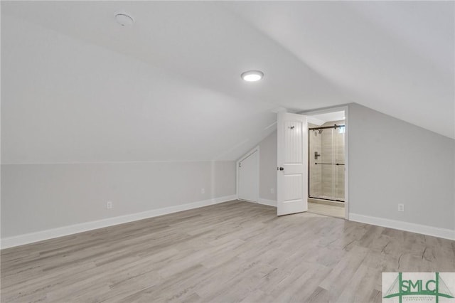 bonus room with baseboards, lofted ceiling, and light wood-type flooring