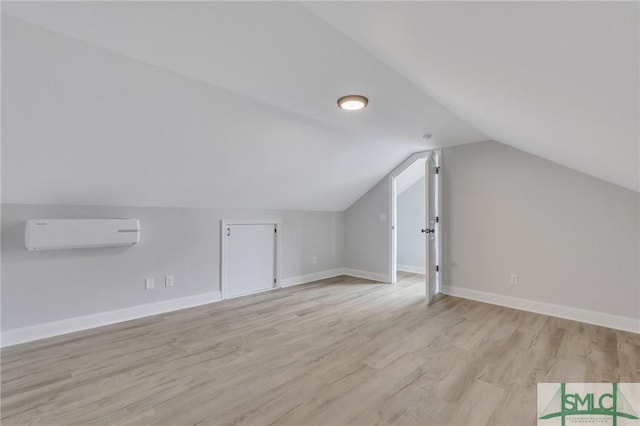 bonus room with an AC wall unit, light wood-style floors, baseboards, and vaulted ceiling