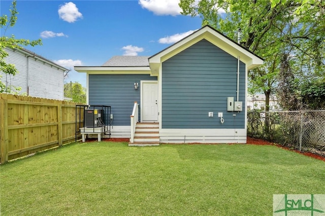 rear view of house featuring a yard, a fenced backyard, and entry steps