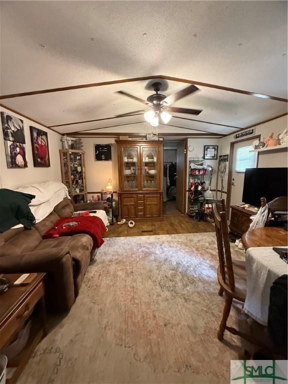 living room with a ceiling fan, wood finished floors, and lofted ceiling