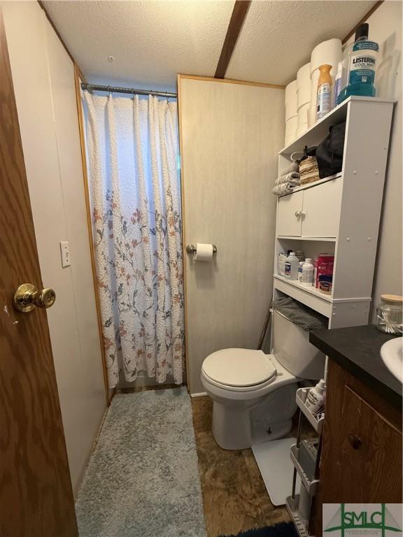bathroom with vanity, toilet, a textured ceiling, and a shower with shower curtain