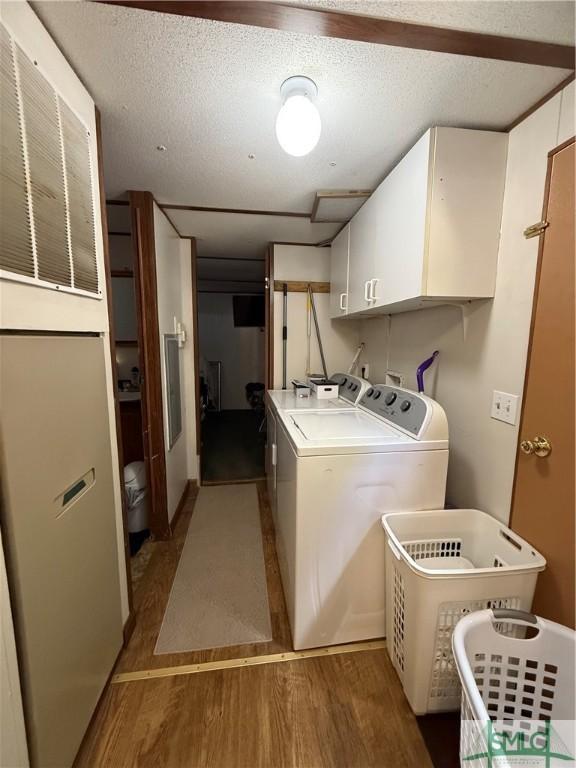 clothes washing area featuring cabinet space, independent washer and dryer, a textured ceiling, and wood finished floors