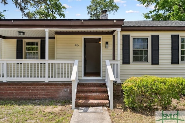 entrance to property featuring a porch and a chimney