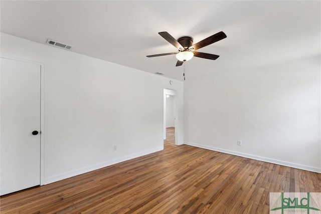 unfurnished room with baseboards, a ceiling fan, wood finished floors, and visible vents