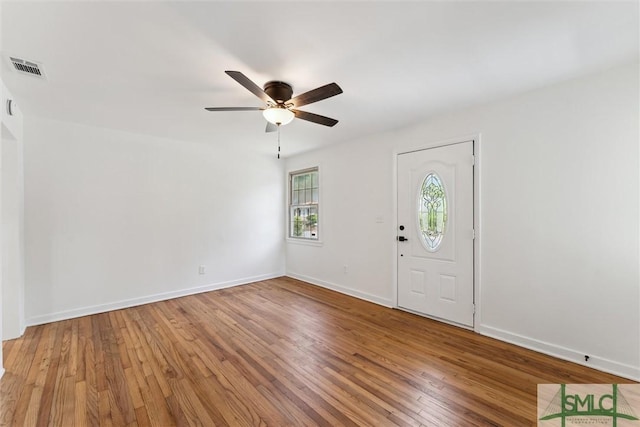 foyer entrance featuring baseboards, a ceiling fan, wood finished floors, and visible vents