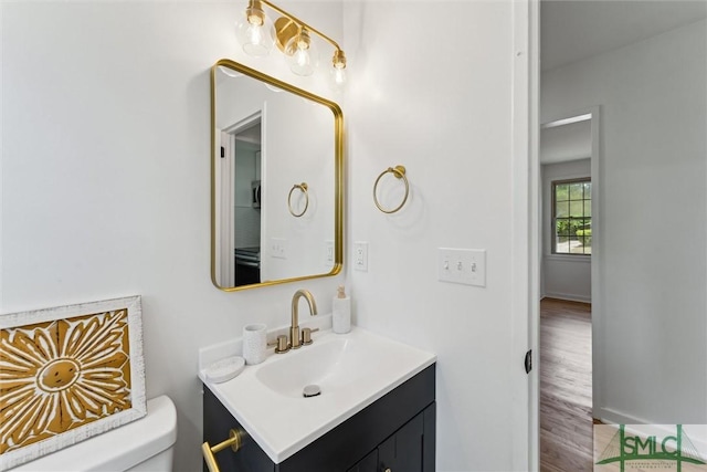 half bath featuring toilet, wood finished floors, and vanity
