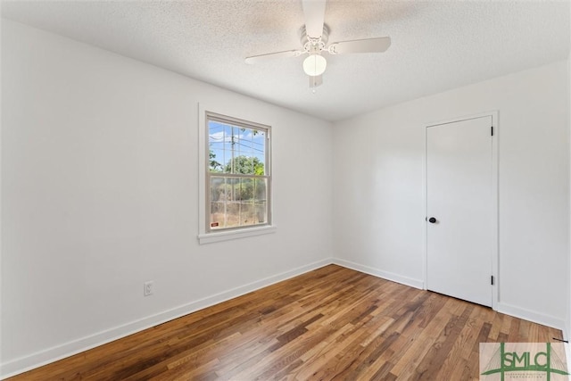 spare room with baseboards, a textured ceiling, and wood finished floors