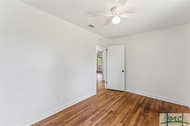 spare room featuring baseboards, ceiling fan, wood finished floors, and visible vents