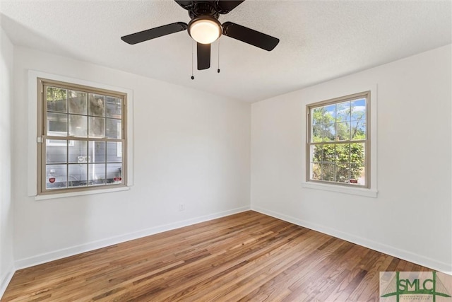 spare room featuring light wood-style floors, baseboards, and a textured ceiling
