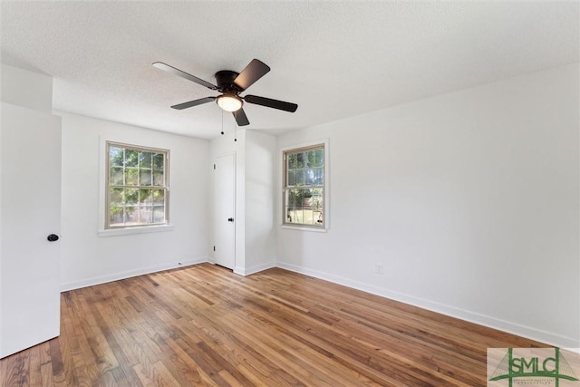 unfurnished room with wood-type flooring, a ceiling fan, baseboards, and a textured ceiling
