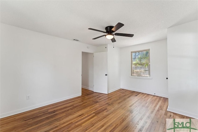 spare room with ceiling fan, baseboards, visible vents, and wood finished floors