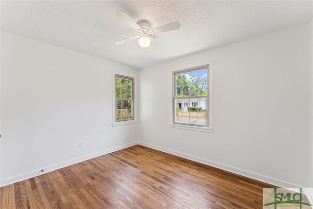 spare room featuring a textured ceiling, baseboards, a ceiling fan, and wood finished floors