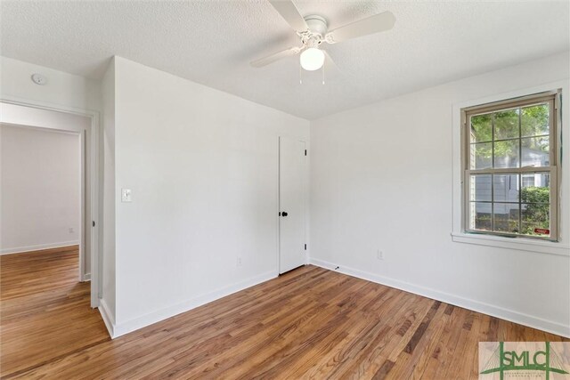 spare room with a textured ceiling, baseboards, ceiling fan, and light wood-style floors