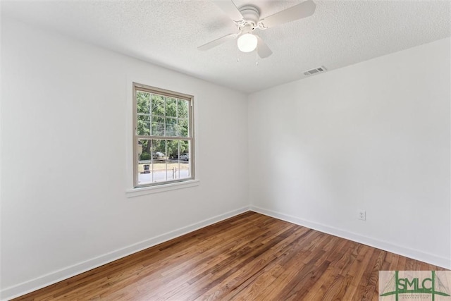 spare room featuring baseboards, a textured ceiling, visible vents, and wood finished floors