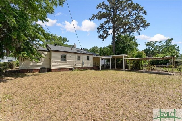 back of property with a detached carport, central AC, a yard, and crawl space